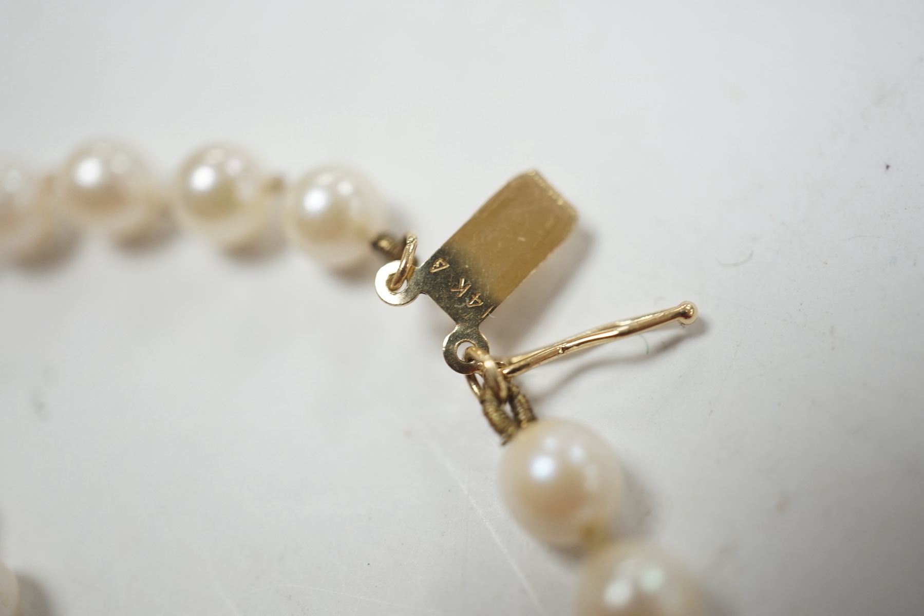 A modern twin strand cultured pearl bracelet, with 14k clasp, 17.5cm, together with two single strand cultured pearl necklaces, with yellow metal clasps. Condition - poor to fair